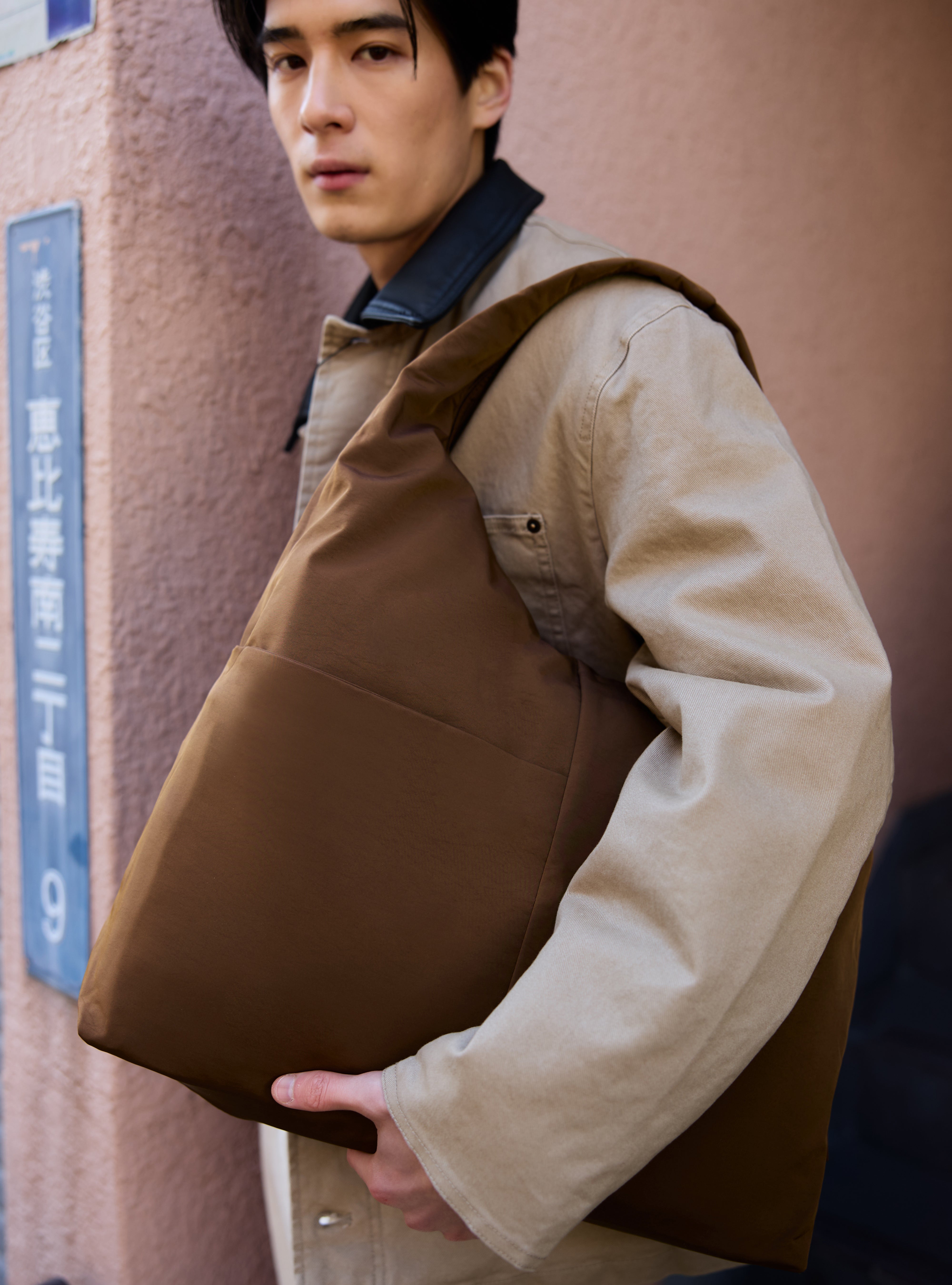 Man carrying the Arc unisex slouchy hobo-style shoulder bag in chocolate brown nylon for work