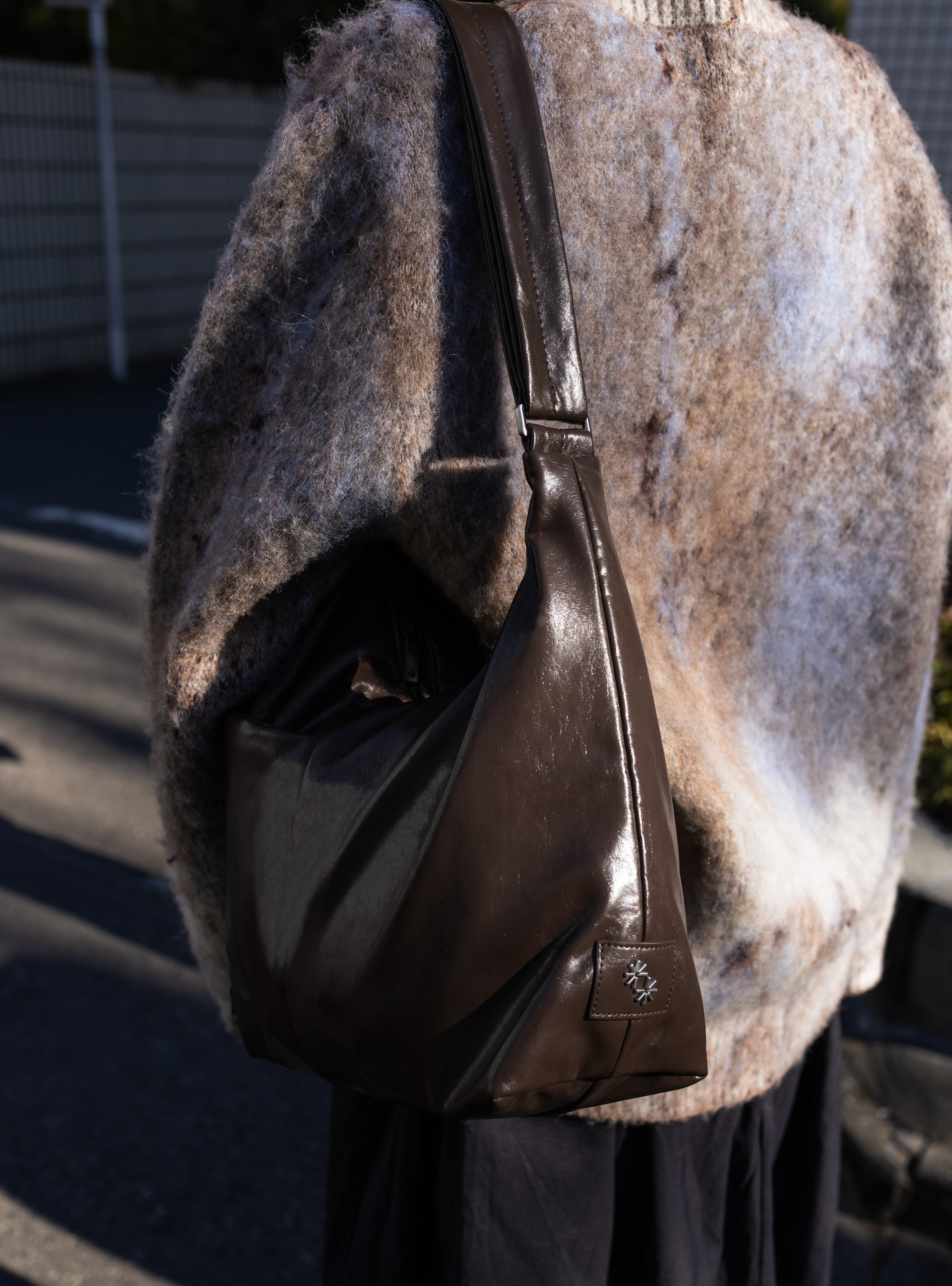 Woman carrying the Midi Arc slouchy hobo bag in dark brown vegan leather as shoulder bag